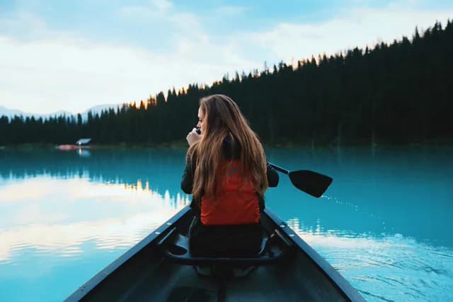 Woman paddling a canoe on a turquoise lake, upscaled