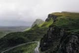 Green ridge and winding road under low cloud, waiting in the queue